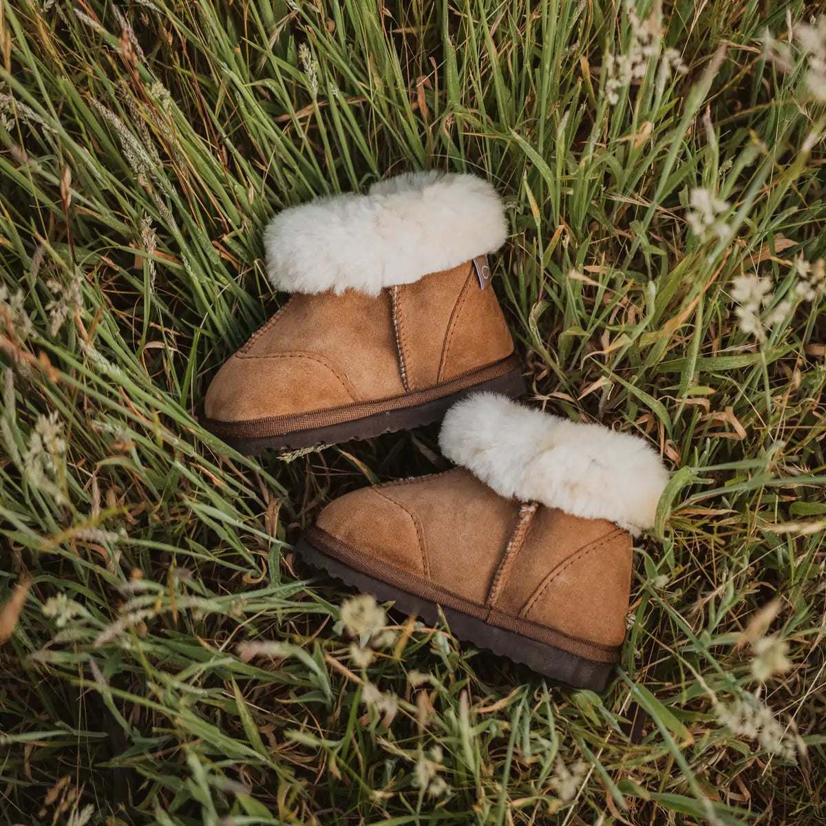 Pair of toddler sheepskin ugg boots in tan with a fluffy wool turn.