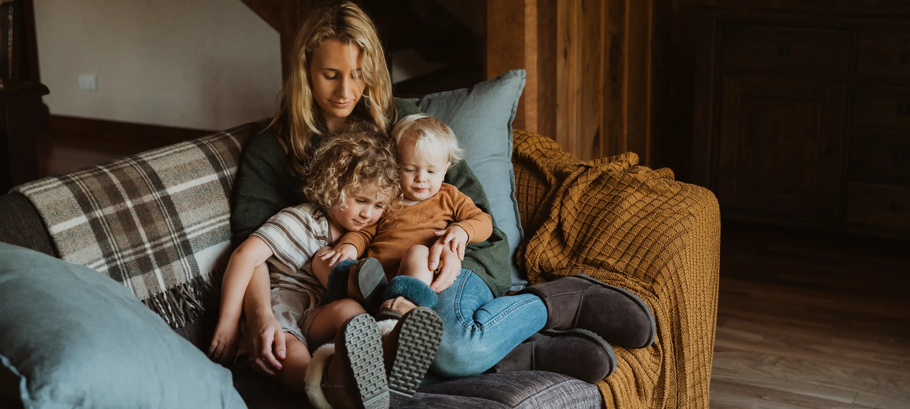 A mum with two kids wearing Jassi uggs in the couch.