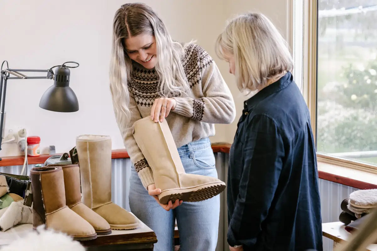 Jassi workers reviewing a finished long ugg boot for quality control.