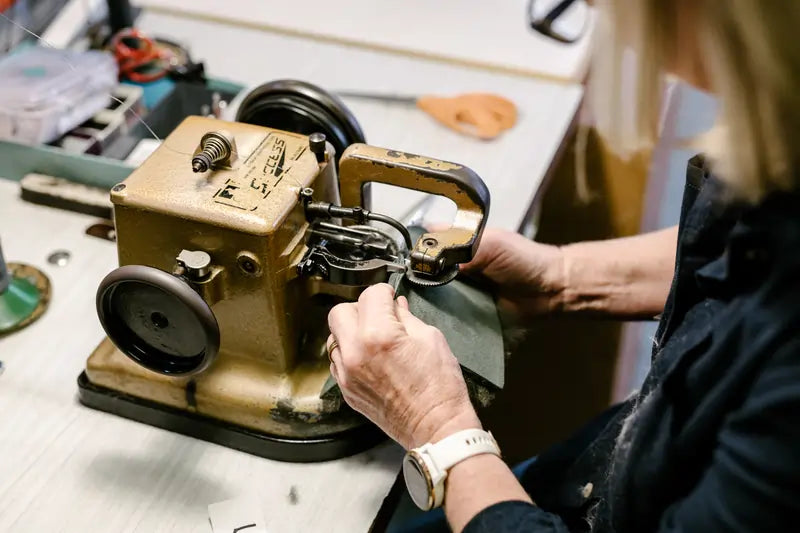 Jassi worker stitching two pieces of olive sheepskin together to make an ugg boot.