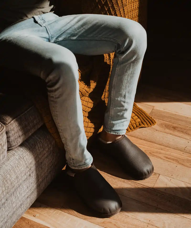 Man sitting on a couch wearing jassi ugg mewels in chocolate leather.