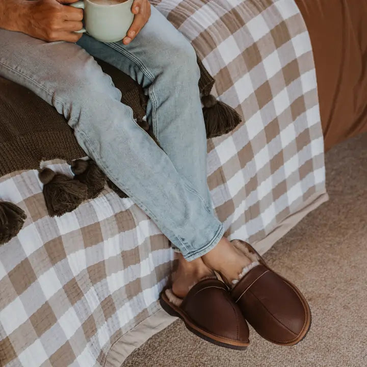 Close up of man having a tea while wearing Jassi ugg leather scuffs in tan. #color_leather tan