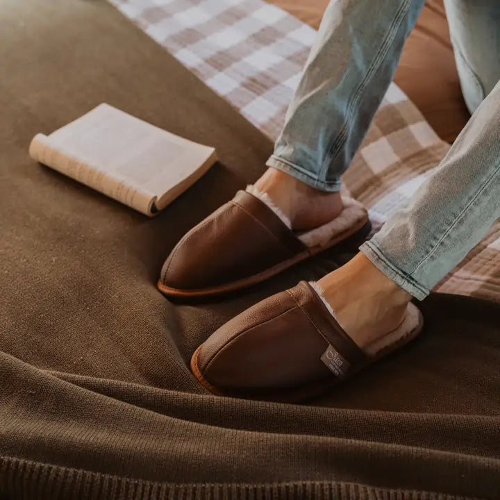 Close up of man relaxing in bed wearing cosy Jassi ugg leather scuffs in tan. #color_leather tan