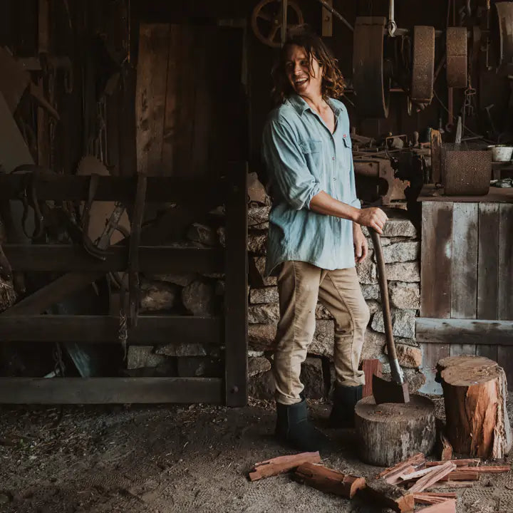 Man chopping wood wearing Jassi short UGG boots on black suede color. #color_black