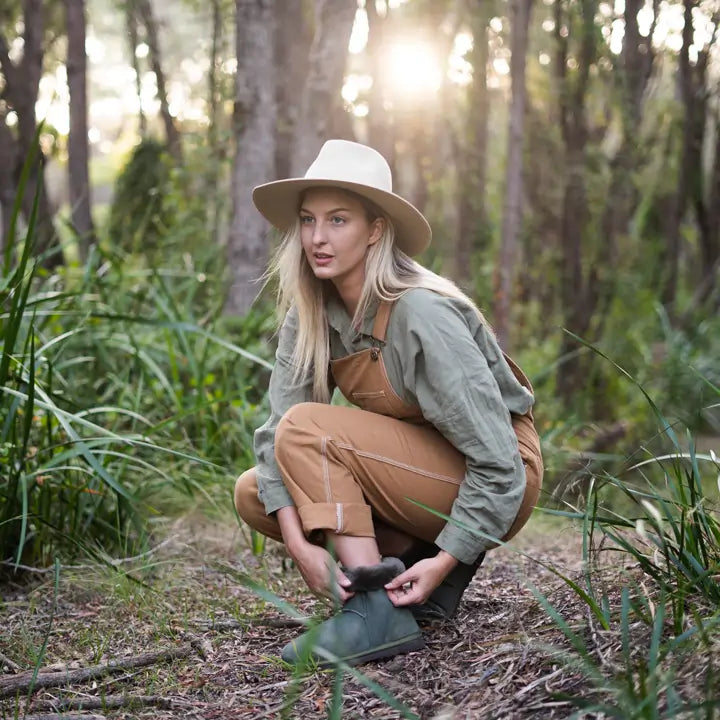 Woman adjusting her Jassi Slipper in suede olive color. #color_olive