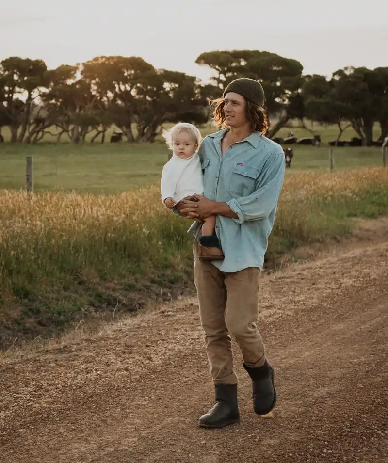 Mab carrying a baby while wearing short leather ugg boots in chocolate.