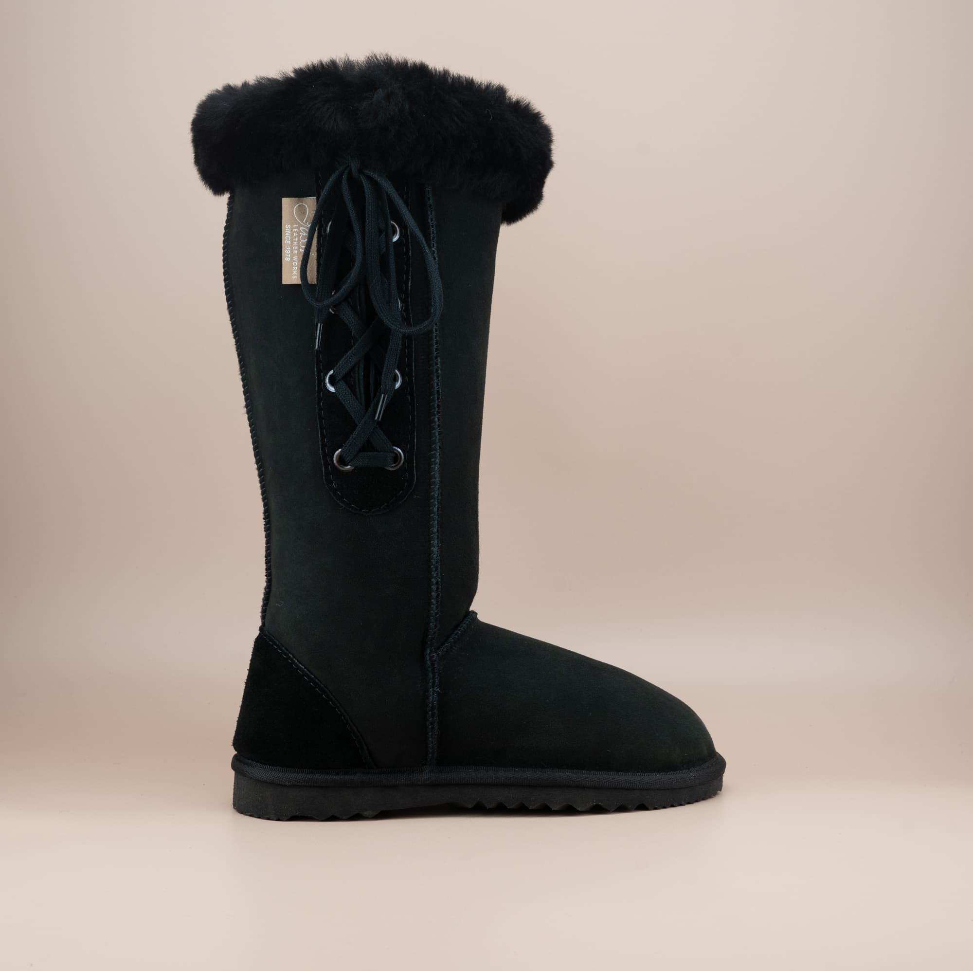 Men's long lace-up ugg boot in color black and soft suede finish with signature wool turn, side view. #color_black