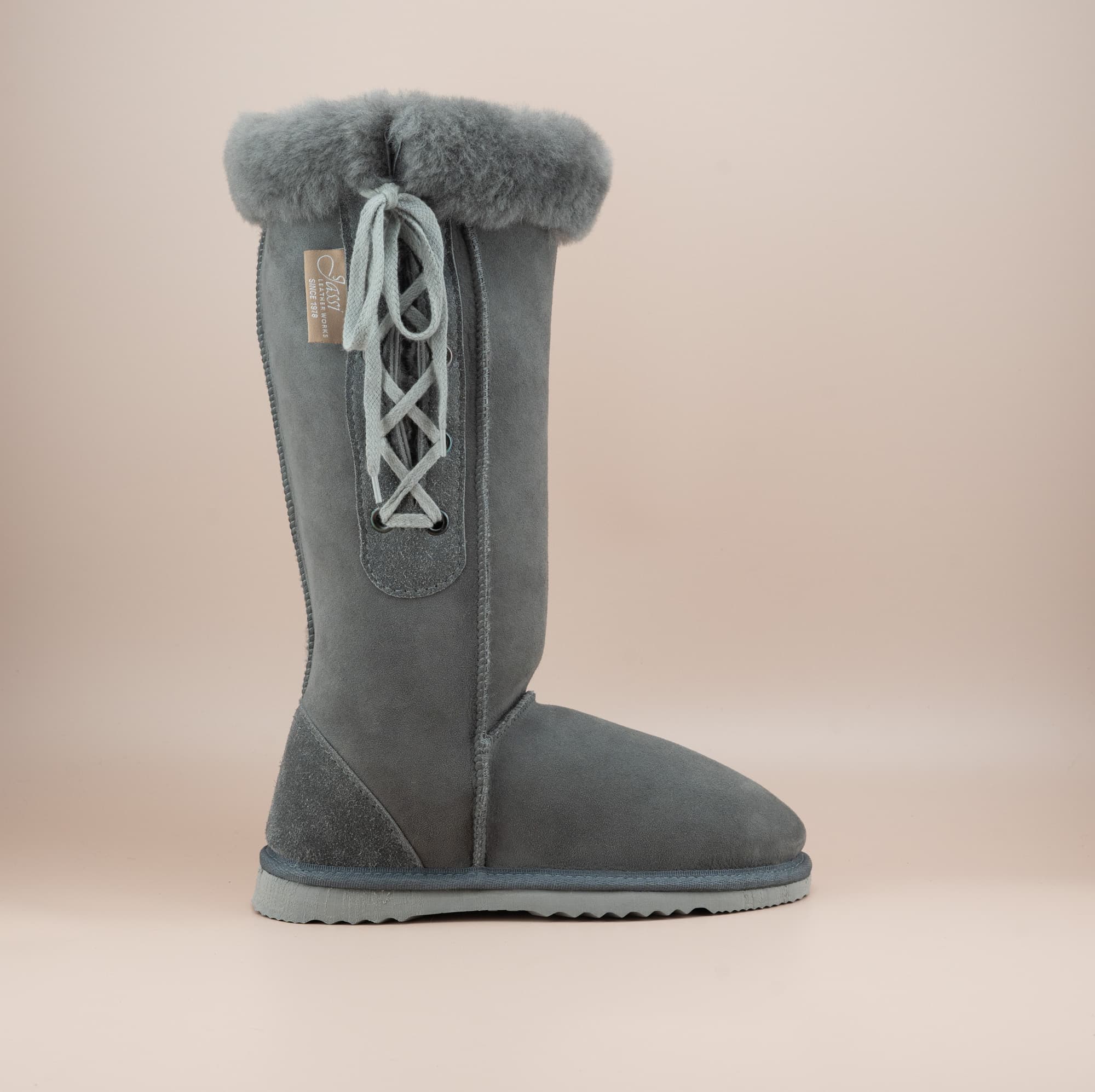 Men's long lace-up ugg boot in color grey and soft suede finish with signature wool turn, side view. #color_grey