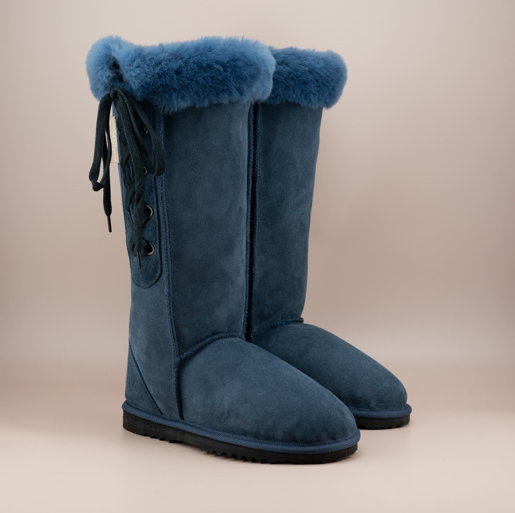 Men's long lace-up ugg boot in color navy and soft suede finish with signature wool turn, front side view. #color_navy