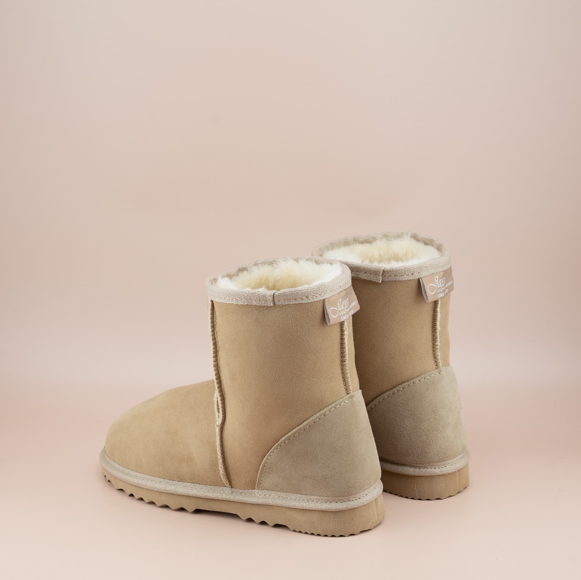 Men's short ugg boot in a sand color and soft suede finish, back view. #color_sand