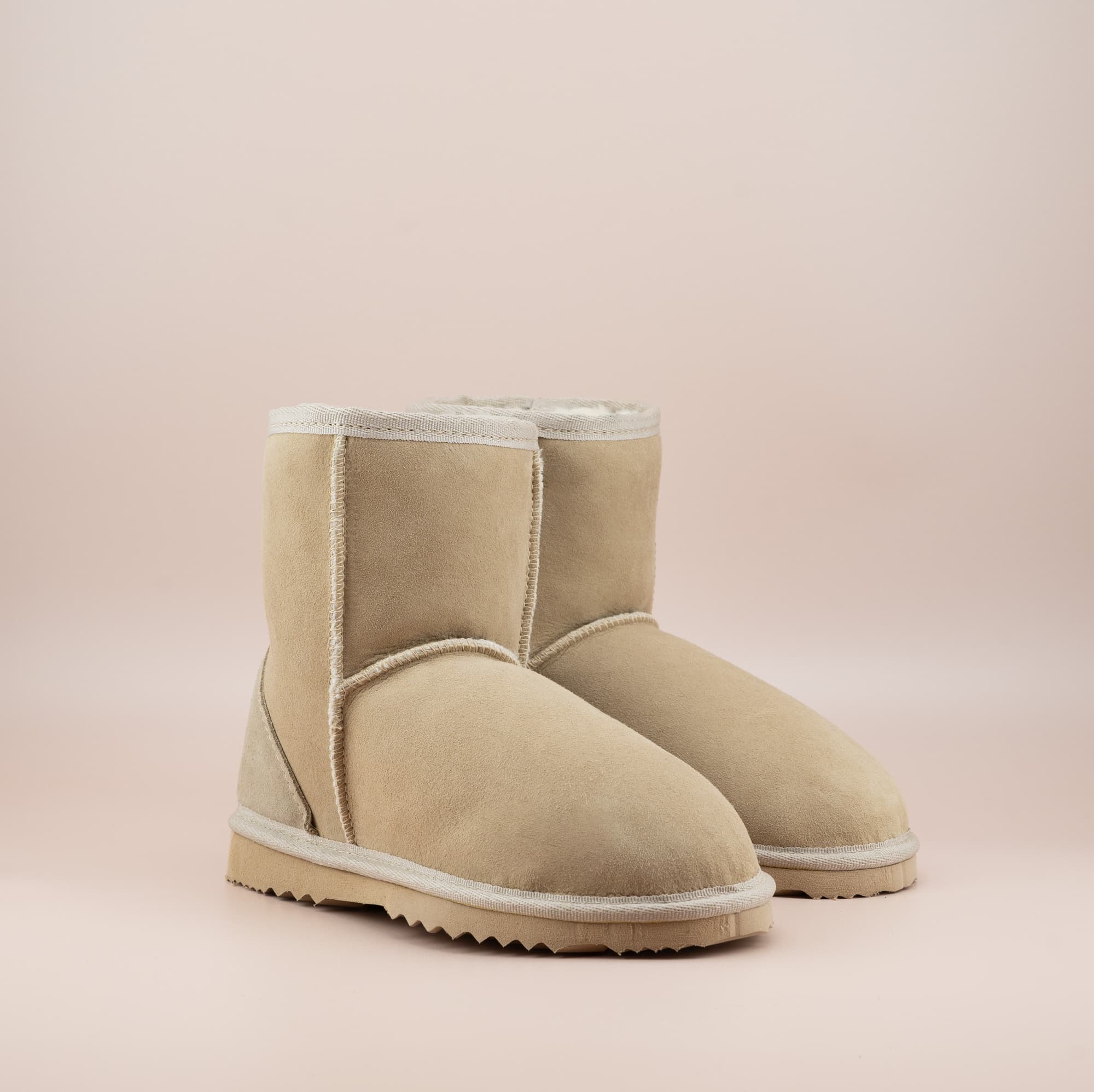 Men's short ugg boot in a sand color and soft suede finish, front side view. #color_sand