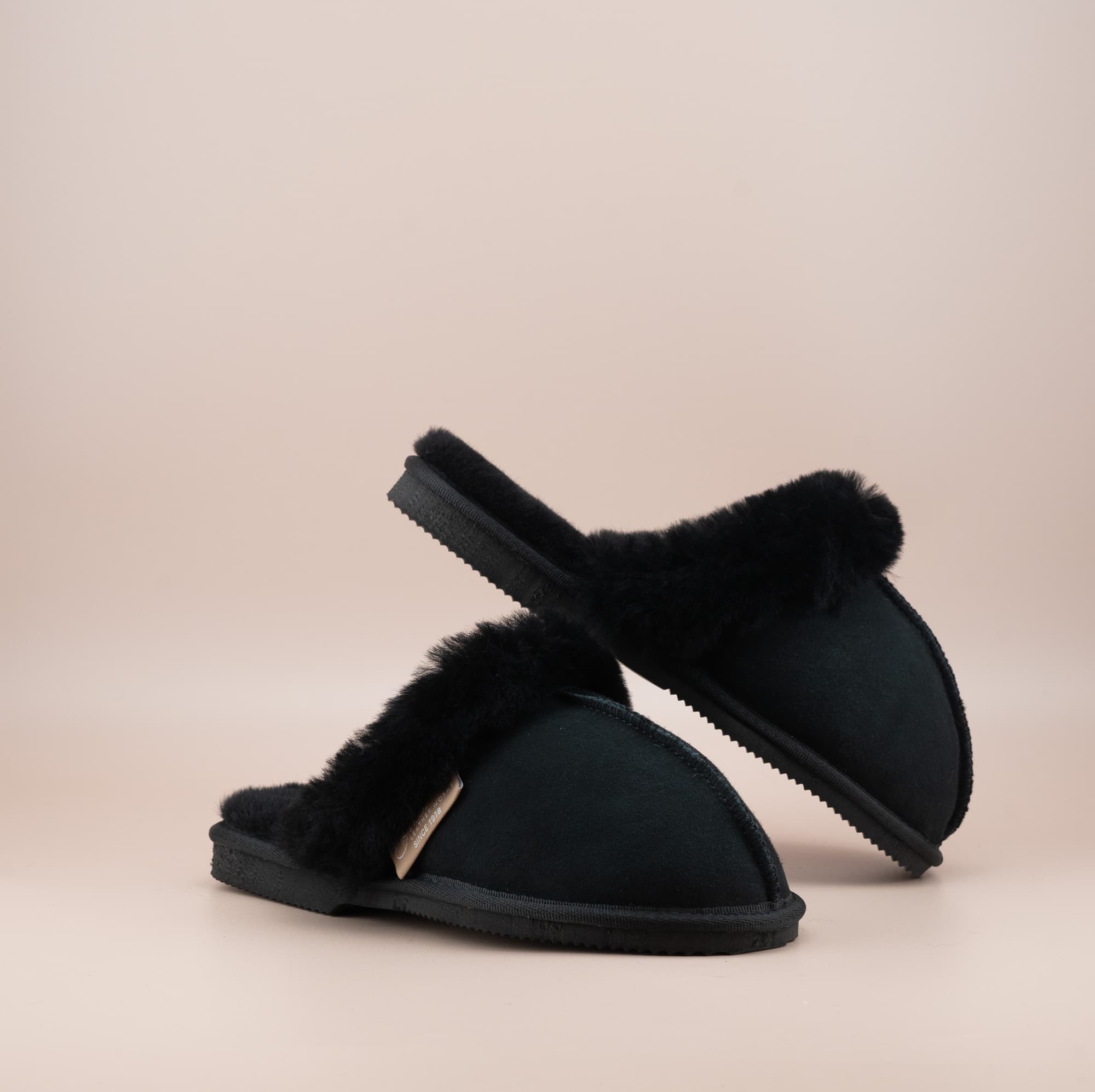 Men's ugg scuffs with a suede finish in black and wool turn, front and side view of the pair. #color_black