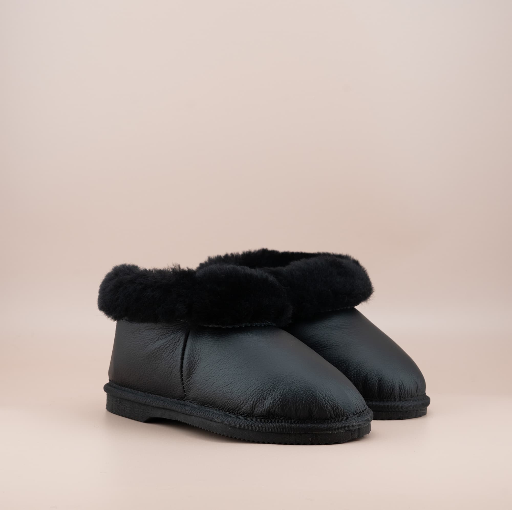 Men's ugg slippers with a genuine leather finish in black and wool turn, side view of the pair. #color_leather black