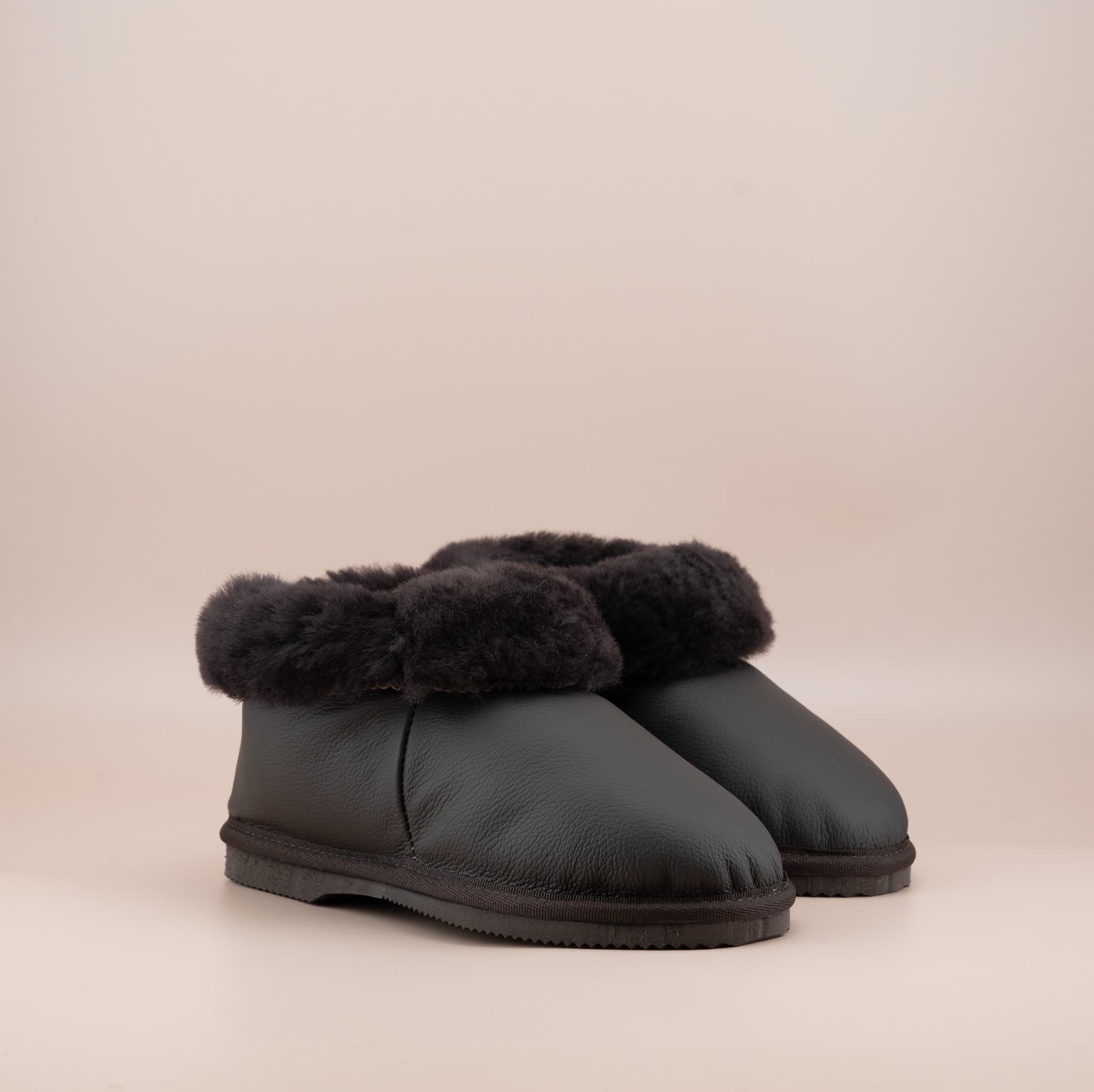 Men's ugg slippers with a genuine leather finish in chocolate and wool turn, side view of the pair. #color_leather chocolate