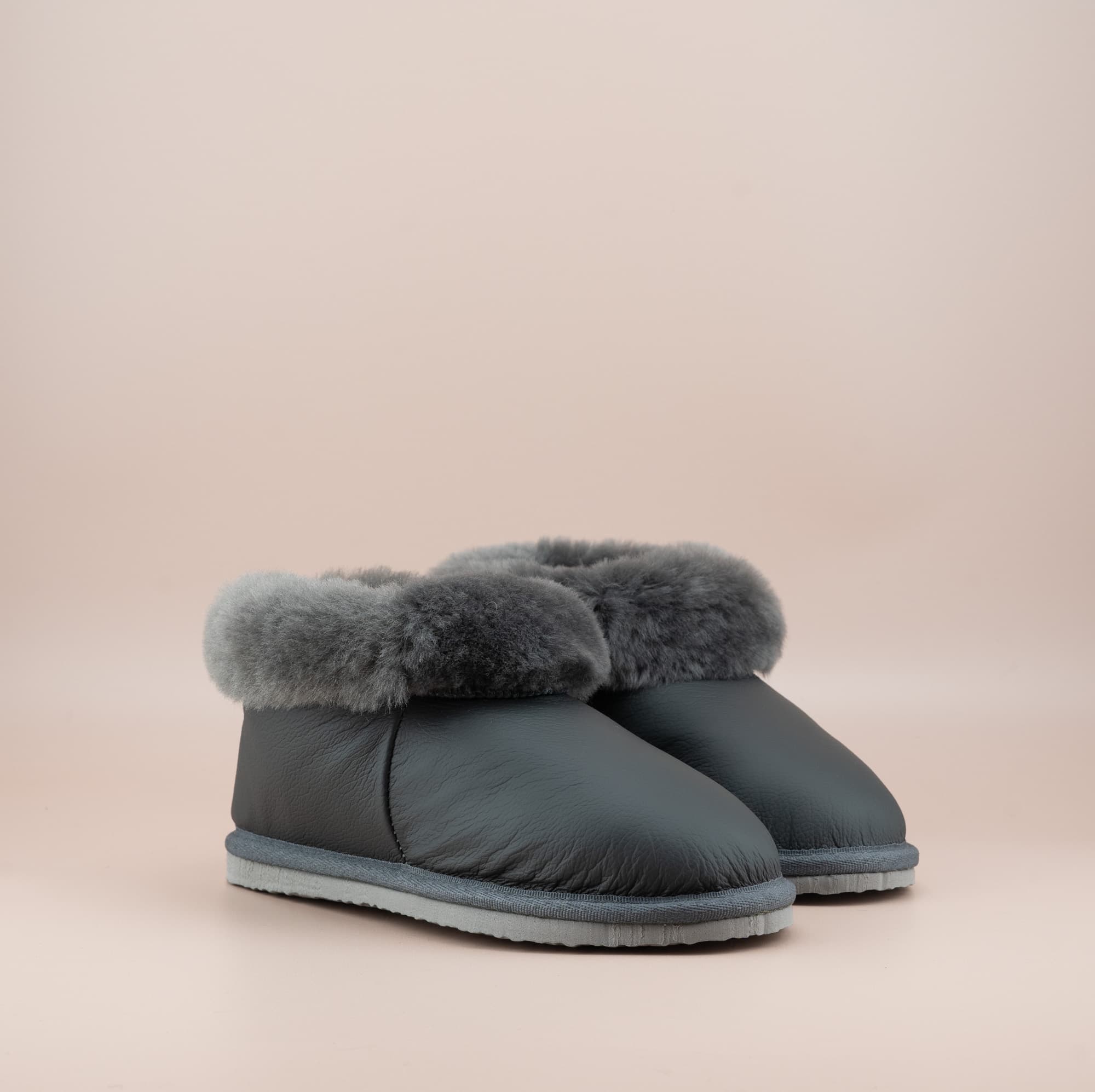 Men's ugg slippers with a genuine leather finish in grey and wool turn, side view of the pair. #color_leather grey