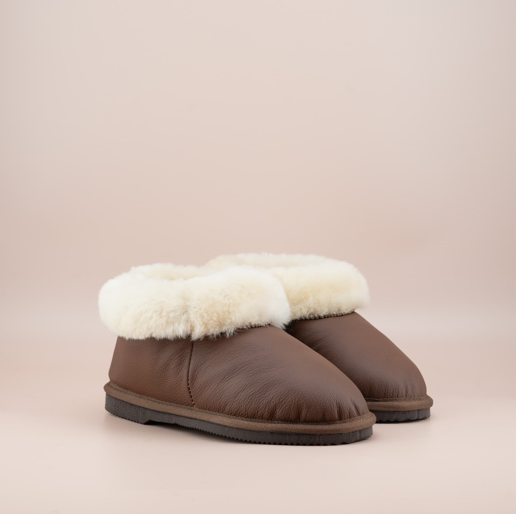 Men's ugg slippers with a genuine leather finish in tan and wool turn, side view of the pair. #color_leather tan