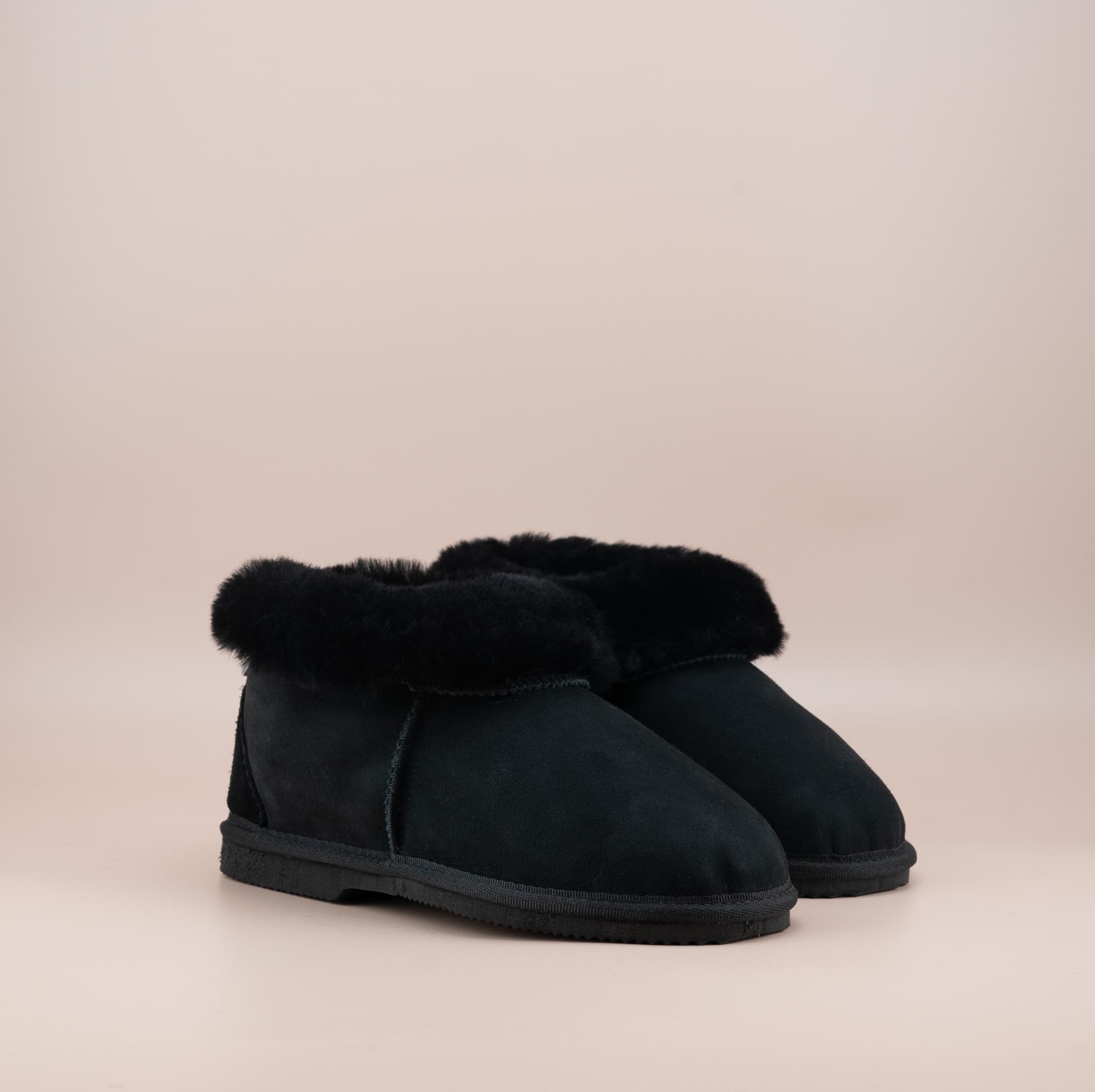 Men's ugg slippers with a suede finish in black and wool turn, side view of the pair. #color_black