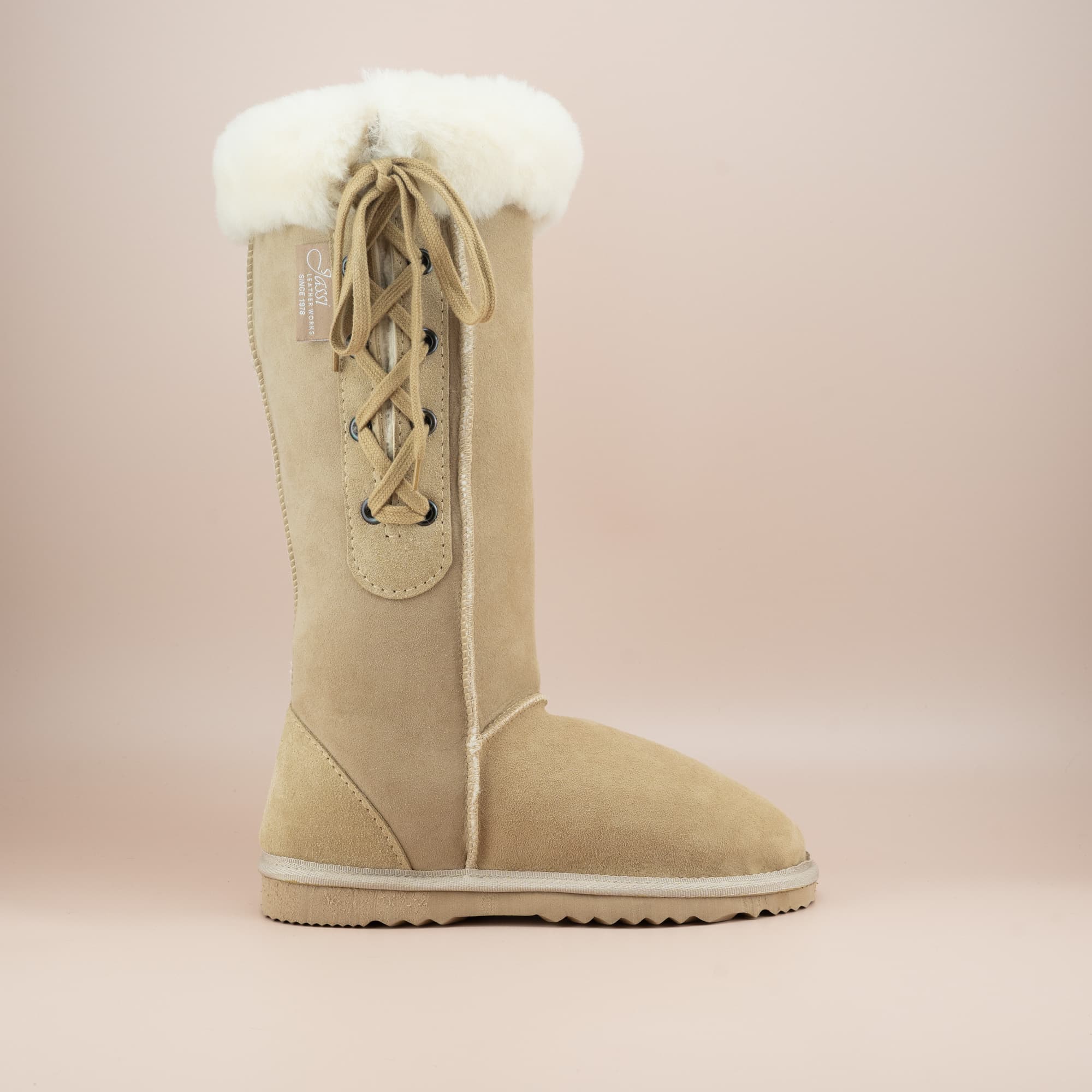 Women's classic long lace-up ugg boot with a cosy wool turn in suede sand color, side view. #color_sand