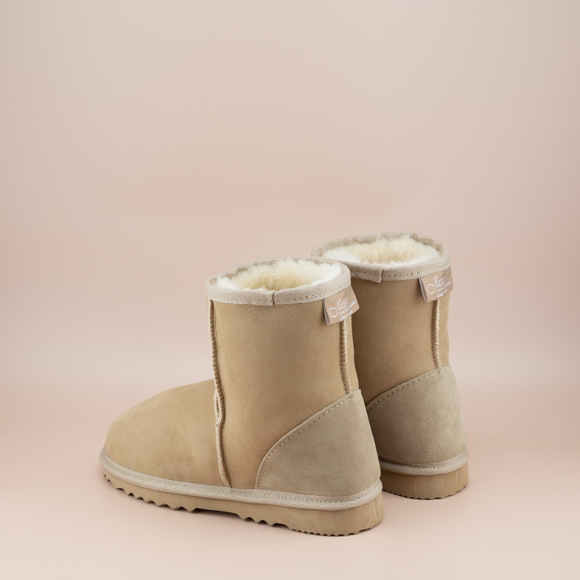 Women's classic short ugg boot in suede sand color, back view. #color_sand